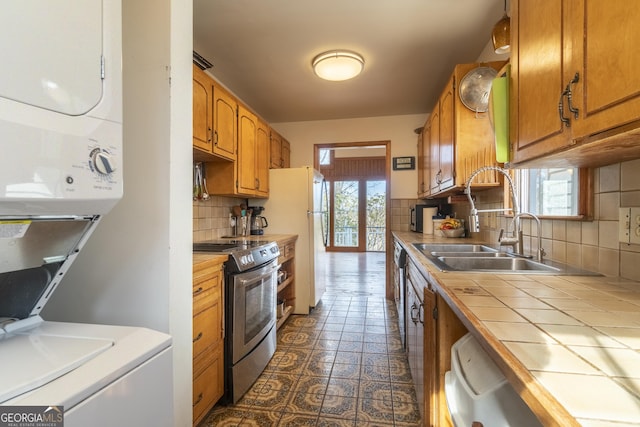 kitchen with tile countertops, plenty of natural light, stainless steel electric range, and a sink