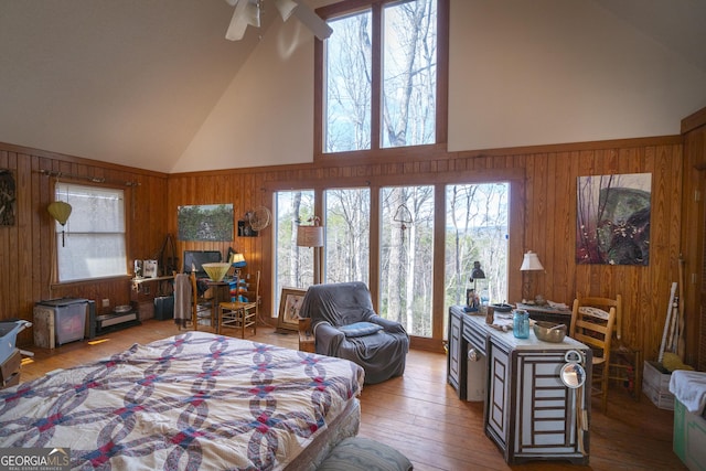 bedroom with high vaulted ceiling, multiple windows, and wooden walls