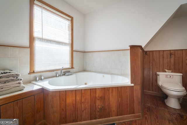 full bath with a wealth of natural light, wainscoting, a jetted tub, and toilet