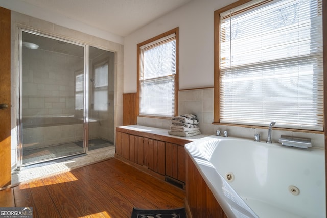 bathroom with a jetted tub, a shower stall, visible vents, and wood finished floors