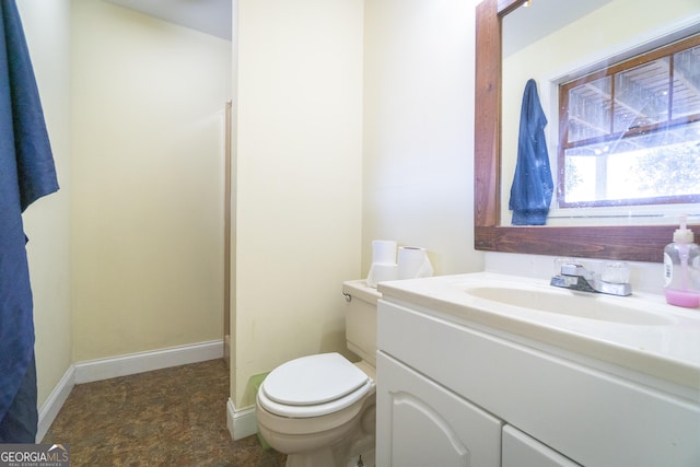 bathroom with toilet, baseboards, and vanity