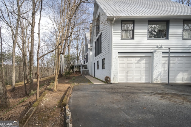 view of property exterior featuring a garage, aphalt driveway, stairs, and stucco siding