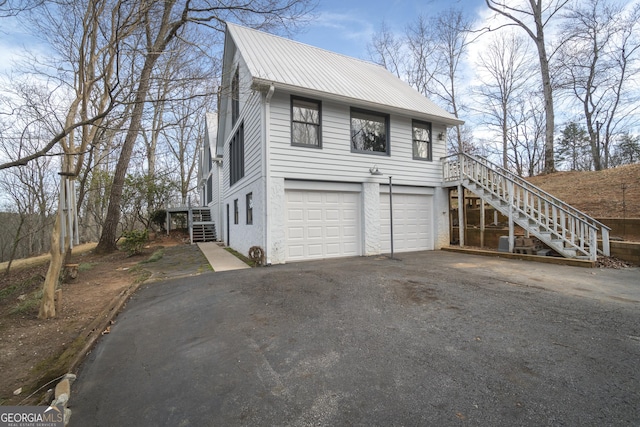 view of home's exterior featuring driveway, a garage, metal roof, stairs, and stucco siding