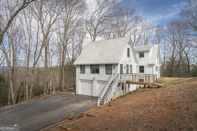 view of front of home with aphalt driveway, metal roof, stairway, and a garage