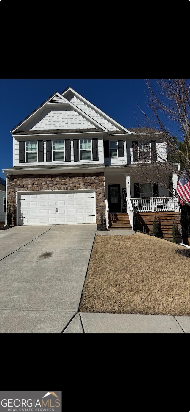 view of front of house featuring a garage, concrete driveway, covered porch, and stone siding