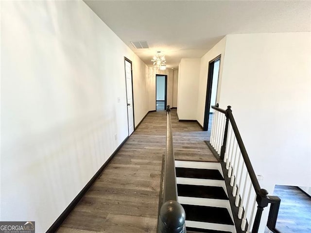 hallway with visible vents, baseboards, and wood finished floors