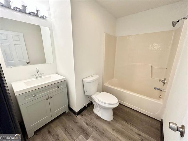 bathroom with baseboards, toilet, shower / tub combination, wood finished floors, and vanity