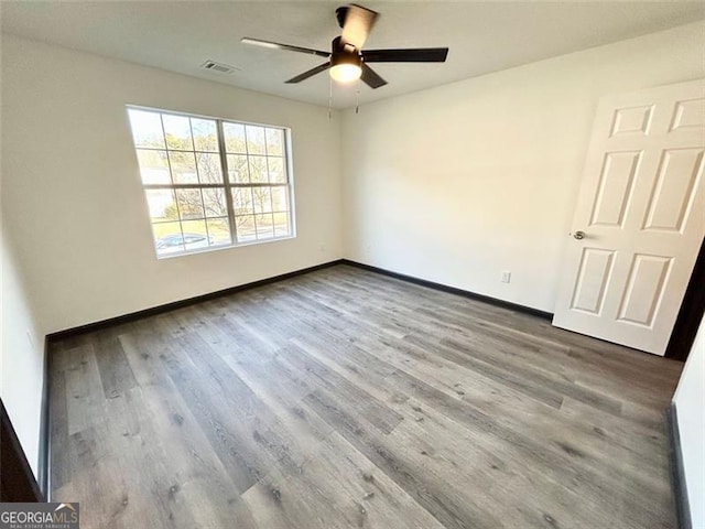 unfurnished room with a ceiling fan, wood finished floors, visible vents, and baseboards