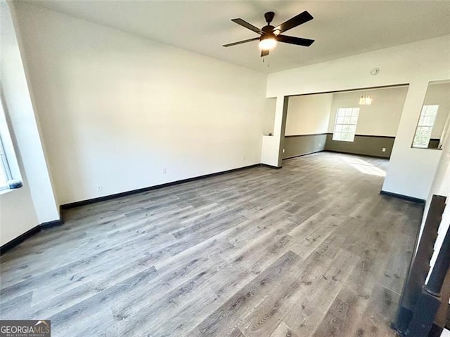 unfurnished room featuring ceiling fan, baseboards, and wood finished floors