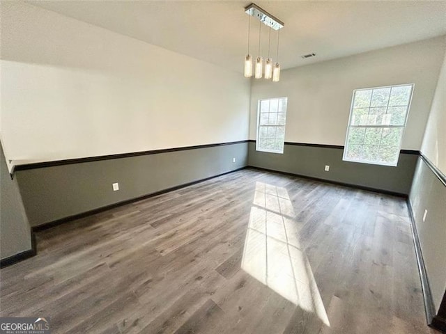 empty room featuring visible vents, baseboards, and wood finished floors