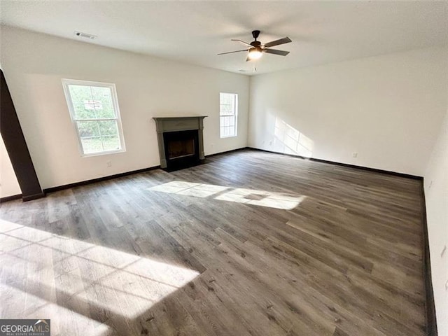 unfurnished living room featuring a fireplace, visible vents, ceiling fan, wood finished floors, and baseboards