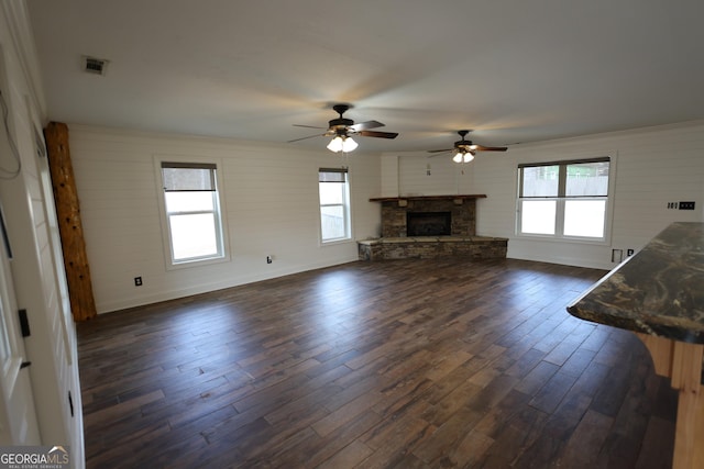 unfurnished living room featuring dark wood finished floors, visible vents, and a healthy amount of sunlight