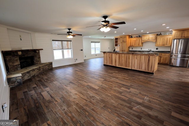 kitchen with dark countertops, open floor plan, dark wood-type flooring, and freestanding refrigerator