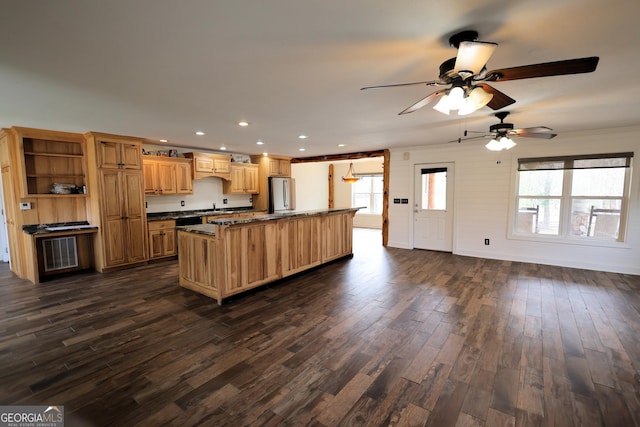 kitchen featuring dark wood finished floors, a kitchen island, freestanding refrigerator, and a sink