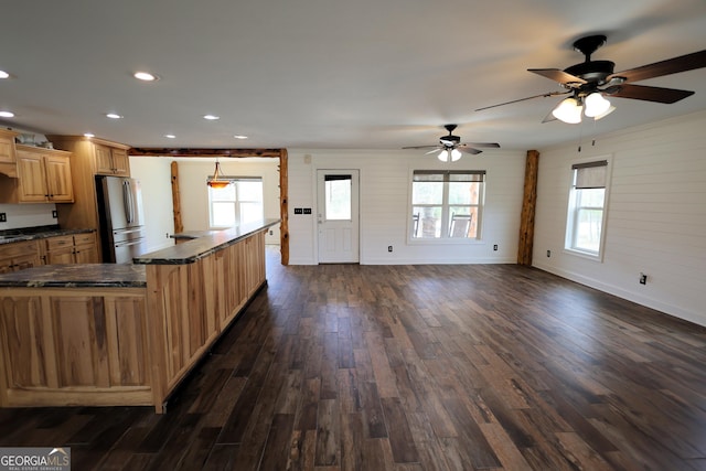 kitchen featuring dark wood finished floors, recessed lighting, freestanding refrigerator, dark countertops, and a center island