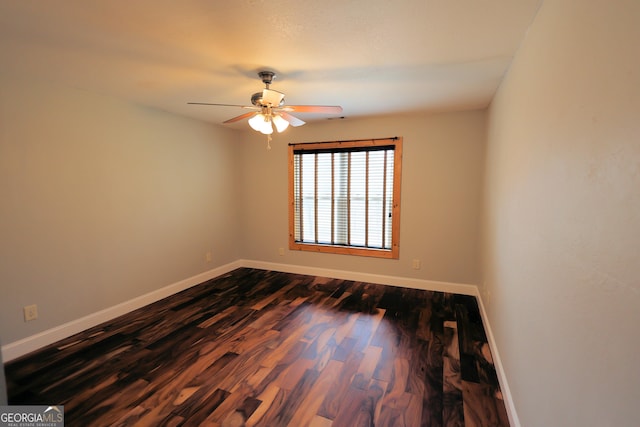 empty room with ceiling fan, dark wood-type flooring, and baseboards