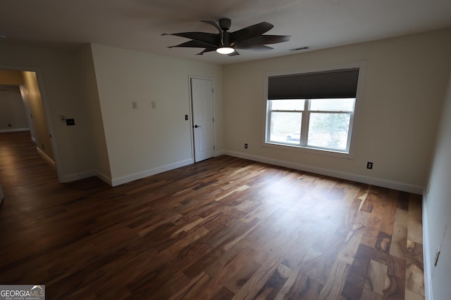 unfurnished room with dark wood finished floors, visible vents, and baseboards