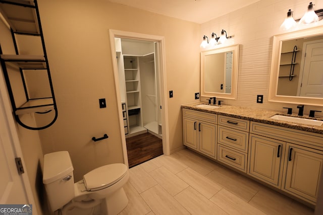 bathroom with a sink, toilet, and double vanity