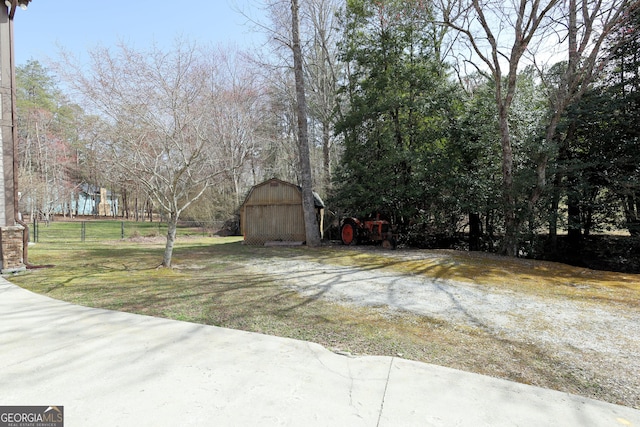 view of yard with an outbuilding, a storage unit, and fence