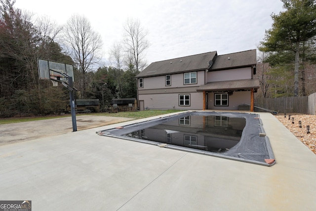 rear view of property featuring concrete driveway, a patio, and fence