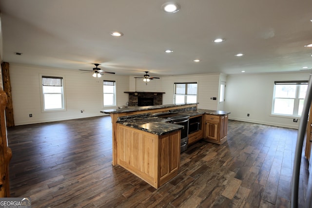 kitchen featuring dark wood-style floors, open floor plan, stainless steel range with electric cooktop, and a fireplace