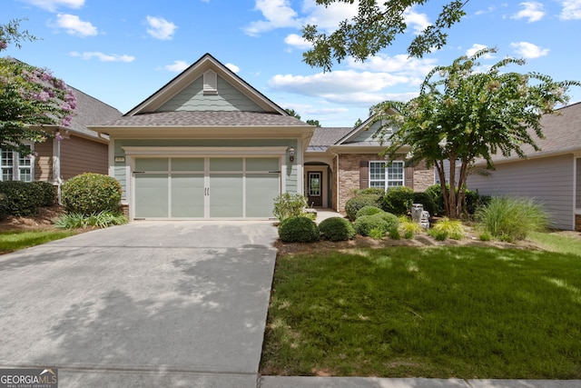 view of front of house featuring a garage, driveway, a shingled roof, stone siding, and a front yard