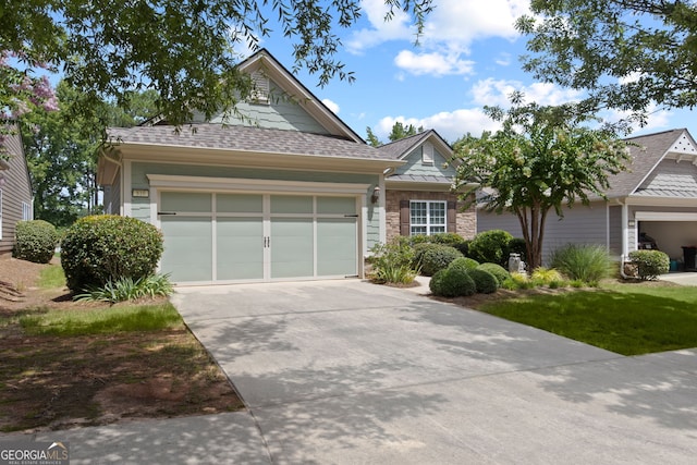 view of front of house with an attached garage, driveway, and a shingled roof