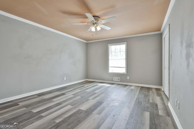 unfurnished room featuring ornamental molding, visible vents, baseboards, and wood finished floors