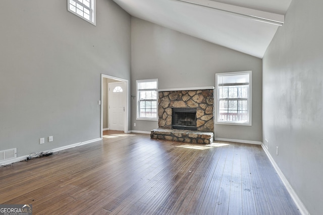 unfurnished living room with wood-type flooring, visible vents, a fireplace, and baseboards