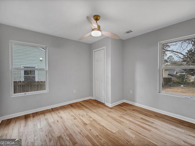 unfurnished bedroom featuring a ceiling fan, visible vents, wood finished floors, baseboards, and a closet