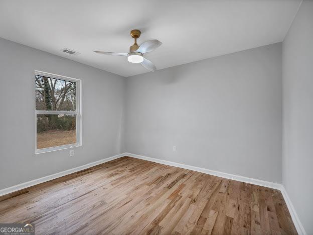 unfurnished room featuring visible vents, ceiling fan, baseboards, and wood finished floors