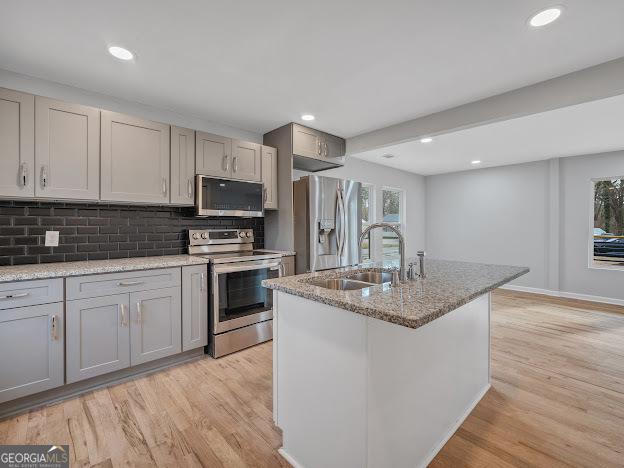 kitchen with a sink, stainless steel appliances, gray cabinets, and light wood finished floors