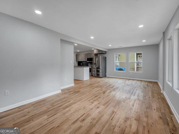 unfurnished living room featuring light wood finished floors, recessed lighting, and baseboards