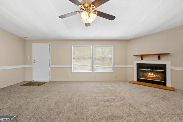 unfurnished living room featuring a glass covered fireplace, carpet flooring, and a ceiling fan