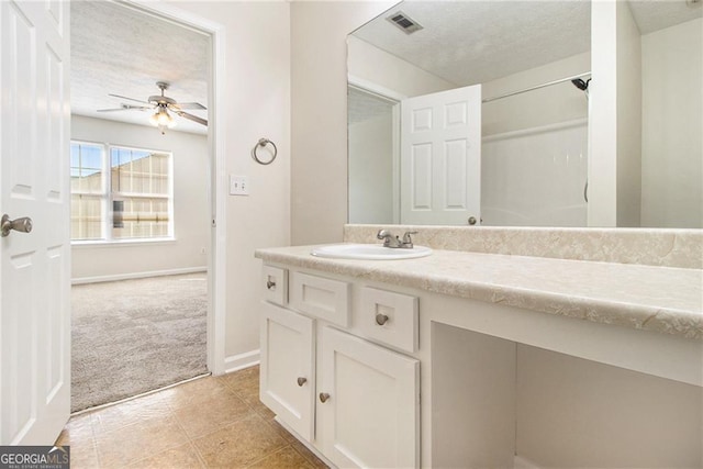 bathroom featuring a textured ceiling, ceiling fan, visible vents, vanity, and baseboards