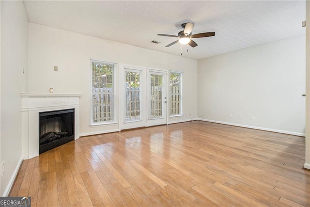 unfurnished living room with ceiling fan, light wood-type flooring, a fireplace, and baseboards