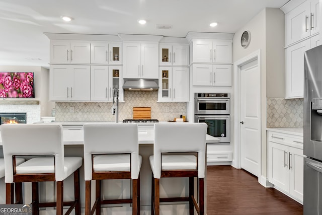 kitchen with light countertops, appliances with stainless steel finishes, white cabinets, and under cabinet range hood