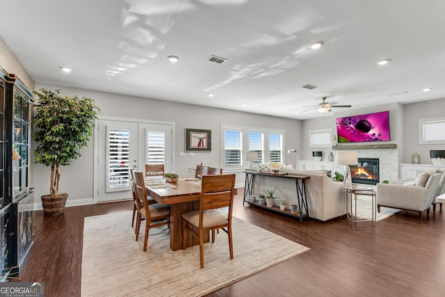 dining room featuring dark wood finished floors, recessed lighting, visible vents, a stone fireplace, and baseboards