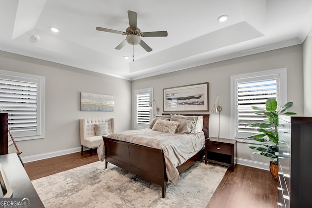 bedroom featuring a raised ceiling, baseboards, and wood finished floors