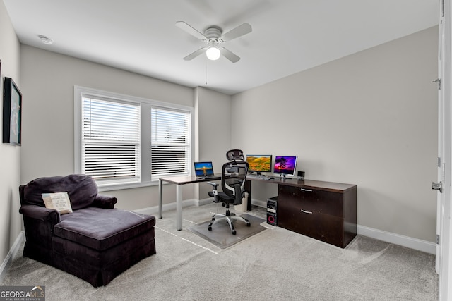 carpeted office space featuring a ceiling fan and baseboards