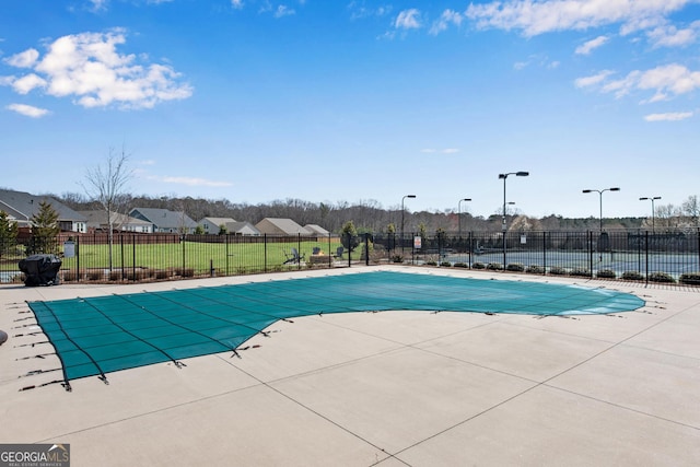 pool featuring a patio area, fence, and a lawn