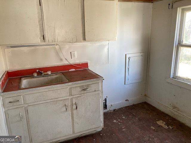 kitchen with plenty of natural light, white cabinets, and a sink