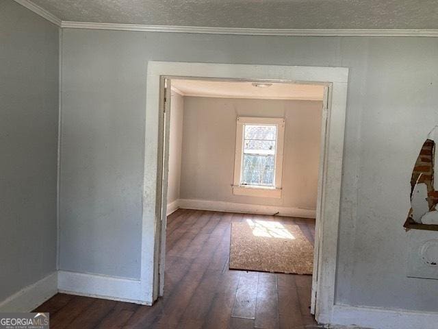 interior space featuring wood-type flooring, crown molding, a textured ceiling, and baseboards