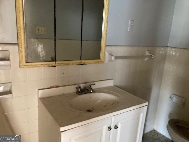 bathroom featuring tasteful backsplash, tile walls, vanity, and toilet