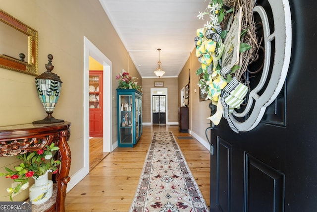 entryway featuring ornamental molding, light wood finished floors, and baseboards