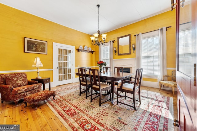 dining room featuring wood-type flooring, a fireplace, and a chandelier