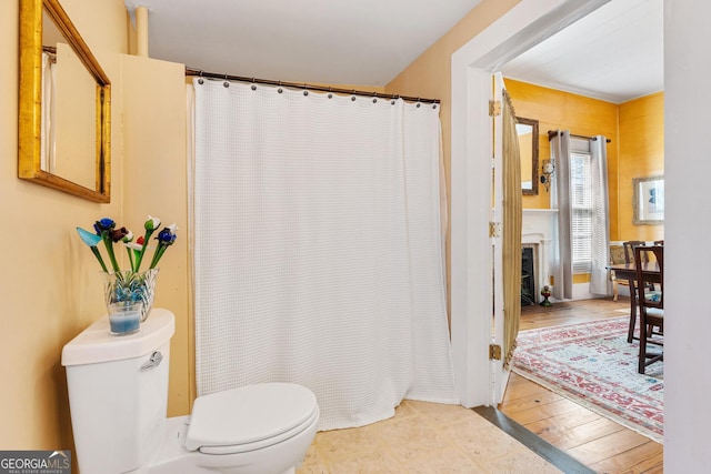 full bathroom with toilet, a fireplace, wood finished floors, and a shower with shower curtain