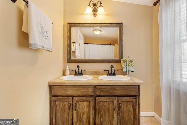 full bathroom featuring double vanity, tile patterned flooring, a sink, and baseboards