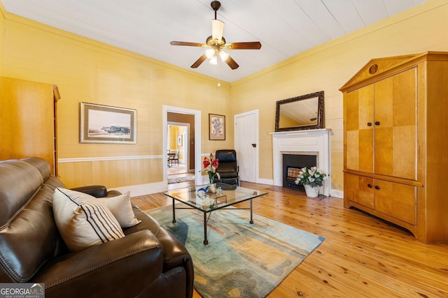 living area featuring light wood finished floors, a fireplace with flush hearth, and a ceiling fan