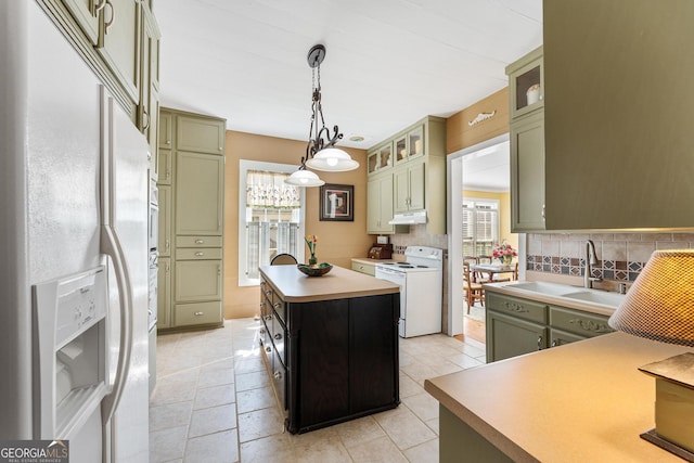 kitchen featuring white appliances, decorative backsplash, under cabinet range hood, green cabinets, and a sink